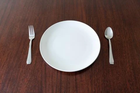 Empty Plate with Spoon and Fork on a table Stock Photos