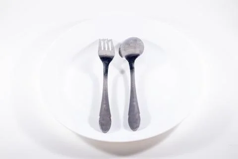 A empty plate with spoon and fork isolated on white background Stock Photos