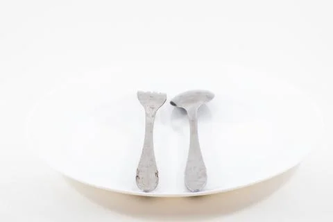 A empty plate with spoon and fork isolated on white background Stock Photos
