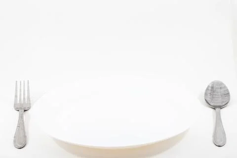 A empty plate with spoon and fork isolated on white background Foto stock