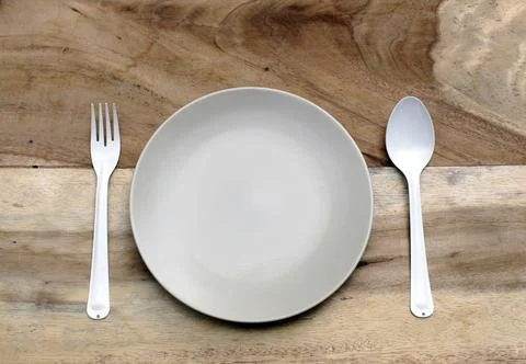 Empty plate with spoon and fork ,top view. on wood background Stock Photos
