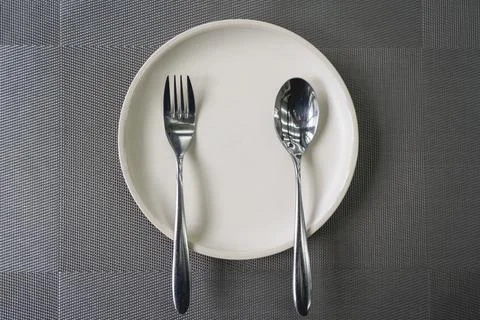 Empty plate spoon and fork on table in restaurant. Stock Photos