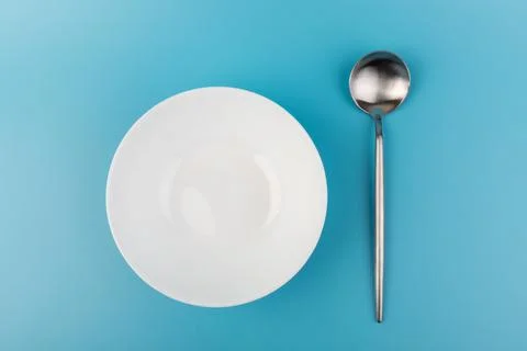 Empty plate with spoon on blue background. Flat lay Dishes for breakfast, lun Stock Photos