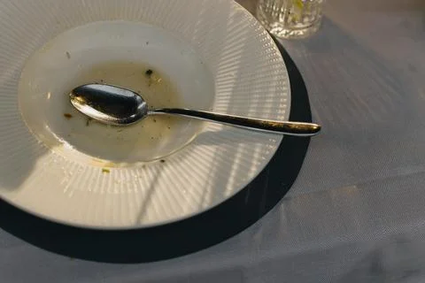 Empty plate with spoon on the table after lunch. Stock Photos