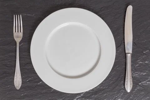 Empty plate with utensils on slate in bird's eye view Stock Photos