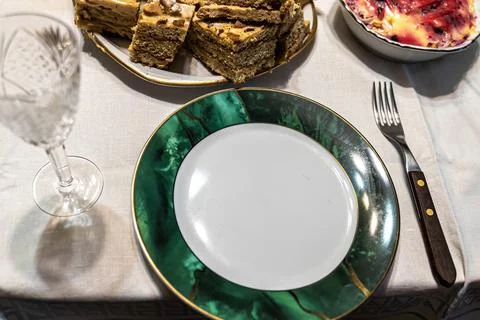 Empty plate waiting for food on table with dessert and crystal glass Foto stock