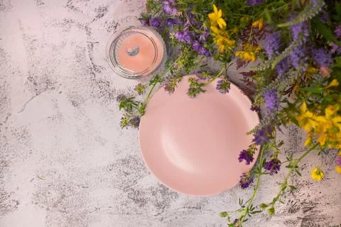 An empty plate in wildflowers on the table. Stock Photos
