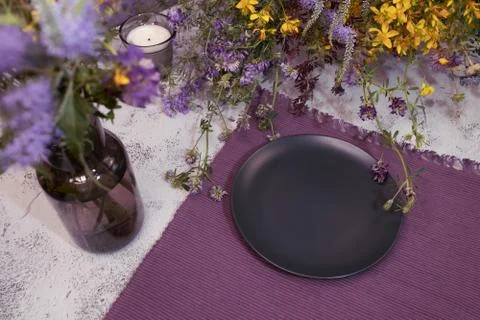 An empty plate in wildflowers on the table. Stock Photos