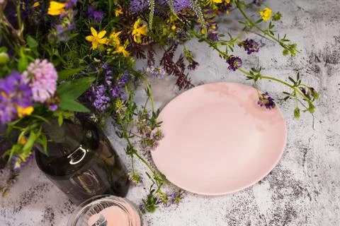 An empty plate in wildflowers on the table. Stock Photos