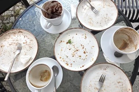 Empty Plates and Coffee Cups on Glass Table - Aftermath of a Meal Stock Photos