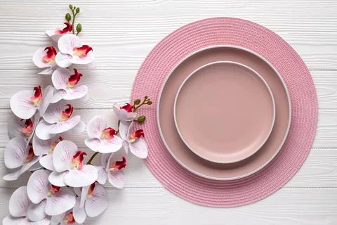 Empty plates and round pink napkin on white wooden table. Place setting wit.. Stock Photos