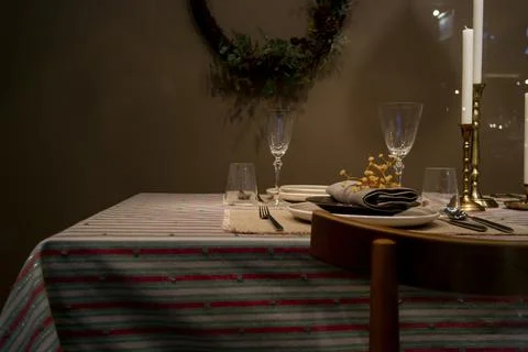 Empty plates and three candles stand on the table on a multicolored striped t Stock Photos