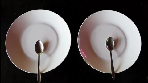 Empty plates with spoons on black background depicting minimalist dining co.. Stock Footage 324959256