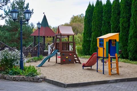 Empty playground with slides and sand in a green park on an autumn day Stock Photos