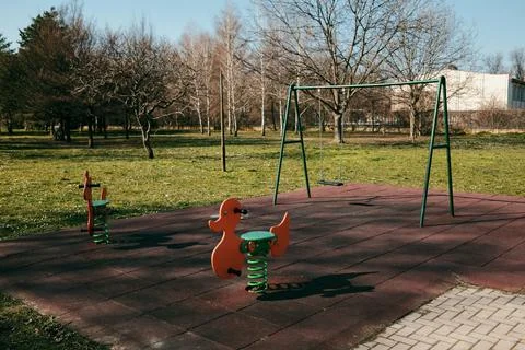 Empty playground with swing and spring riders in a quiet park. Outdoor recrea Stock Photos