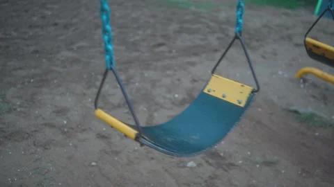 Empty playground swing gently moving in an outdoor park, creating a peaceful Stock Footage 341756130