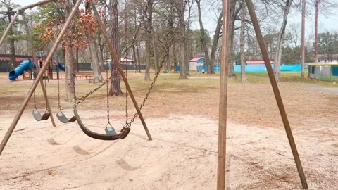 EMPTY PLAYGROUND SWING WITH ONE SWING IN MOTION Stock Footage 182480564