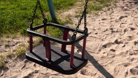 Empty Playground Swing Set Motionless Seat and Chains Casting Shadow on San.. Stock Footage 335616166