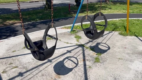 Empty Playground Swings Casting Long Shadows on Sunny Day Stock Footage 346484257