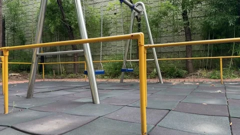 Empty Playground Swings Moving Gently After Rain by Stone Wall 库存影片 342736480