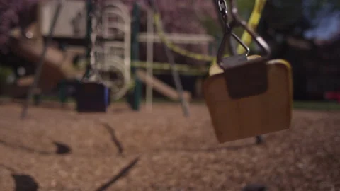 Empty playground swings surrounded by caution tape during a quarantine Video stock 130383141