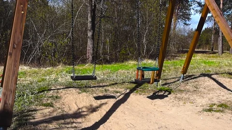 Empty Playground Swings Swinging in the Wind on a Sunny Day Stock Footage 335189930