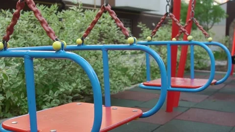 Empty playground, two red-blue swings, motionless. Stock Footage 229893674