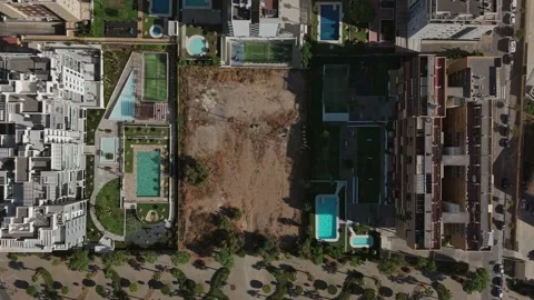 Empty plot of land surrounded by buildings with swimming pools, aerial birds Vídeos de archivo 314721526