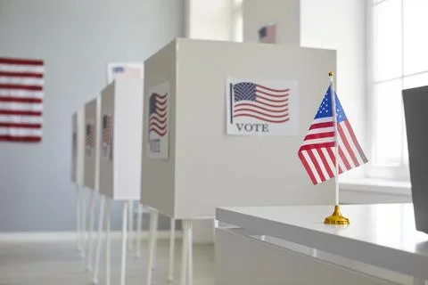 Empty polling station with white voting booths and American flag. Elections in Stock Photos