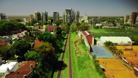 Empty rail road track, railway in green grass among city buildings in summer Vídeos de archivo 262973707