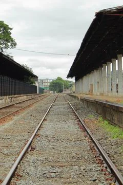 Empty railroad track going through old city station. Perspective view Stock Photos