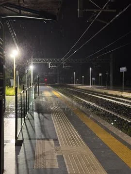 Empty Rainy Railway Platform at Night with Tracks and Station Lights Perspe.. Stock Photos