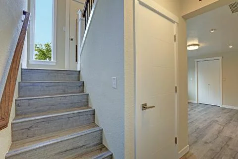Empty rambler style home features gray wood staircase with wood stair rails t Stock Photos