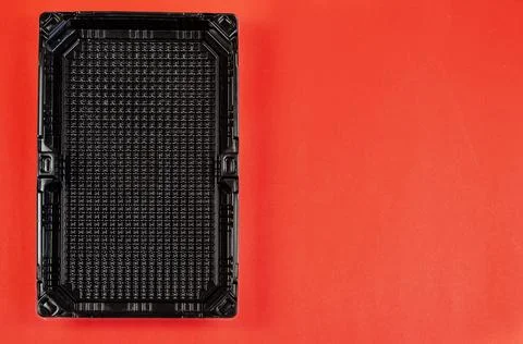 Empty rectangular black plastic container for products on a red background. Stock Photos
