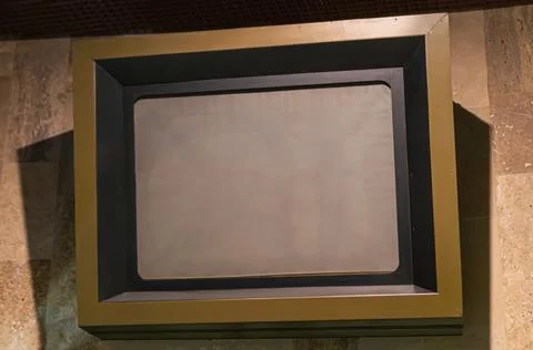 An empty rectangular display frame mounted on a textured, tiled surface. Th.. Stock Photos