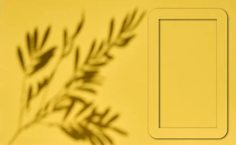 Empty rectangular frame and shadow of a plant branch on a yellow background.. Stock Photos