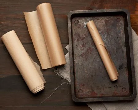 Empty rectangular metal pan and rolls of brown parchment paper Stockfoto's