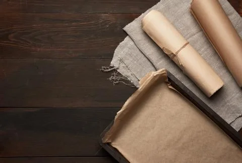 Empty rectangular metal pan covered with brown parchment paper and paper roll Foto stock