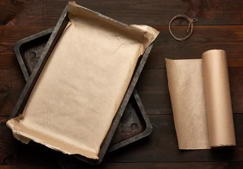 Empty rectangular metal pan covered with brown parchment paper and paper roll Foto stock