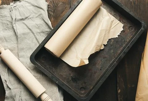 Empty rectangular metal pan covered with brown parchment paper and paper roll Foto stock