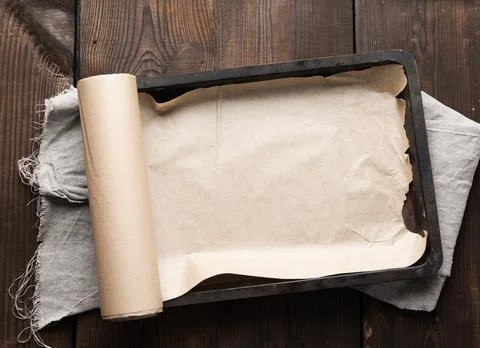 Empty rectangular metal pan covered with brown parchment paper and paper roll Foto stock