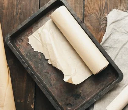 Empty rectangular metal pan covered with brown parchment paper and paper roll Foto stock