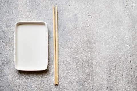 Empty rectangular plate and bamboo chopsticks on gray background with copy sp Stock Photos