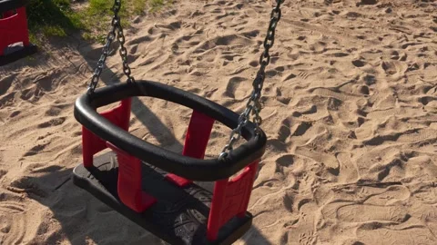 Empty Red and Black Child Swing Set Resting on Sandy Playground Ground Dayt.. Stock Footage 335616159