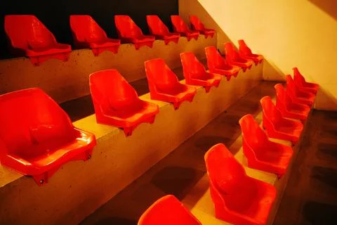 Empty red arena chairs aligned in rows with strong symmetry and vivid color.. Stock Photos