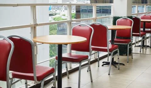 Empty red chairs and round wooden tables in high building Stock Photos