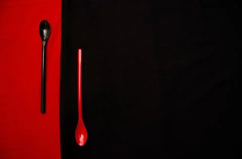 Empty Red colored desert spoon on Black background and Empty Black colored de Foto stock