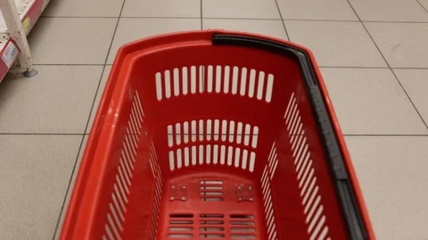 Empty red plastic shopping basket or shopping cart or trolley rolls across the t Stock Footage 119915965