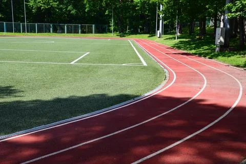 Empty Red Running Track Curve Artificial Turf Football Field Green Trees Stock-Fotos