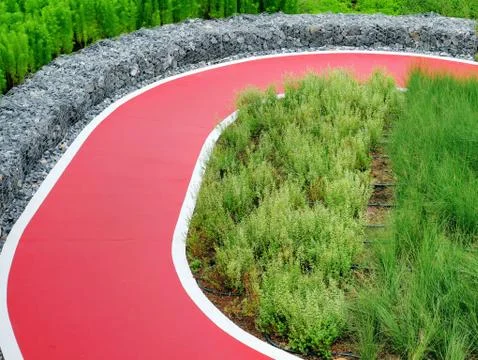 Empty Red Single Lane Road for Biking Through Plants and Bushes in the Park Stock Photos